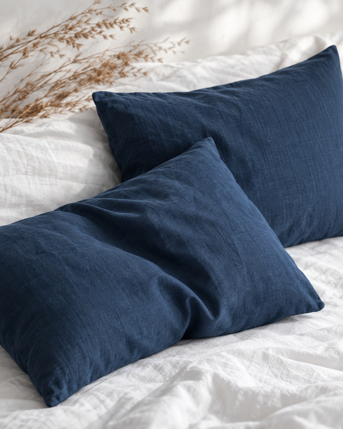 Taies d'oreiller en lin bleu nuit sur lit blanc